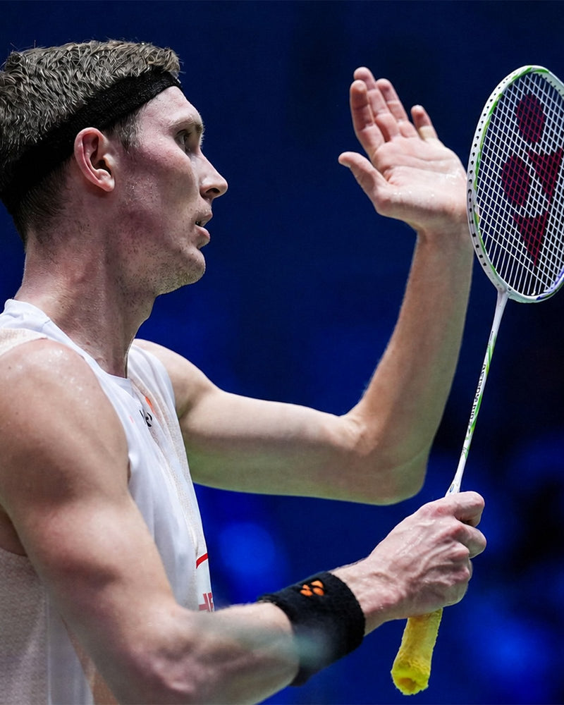 Viktor Axelsen on court holding his white Yonex racket
