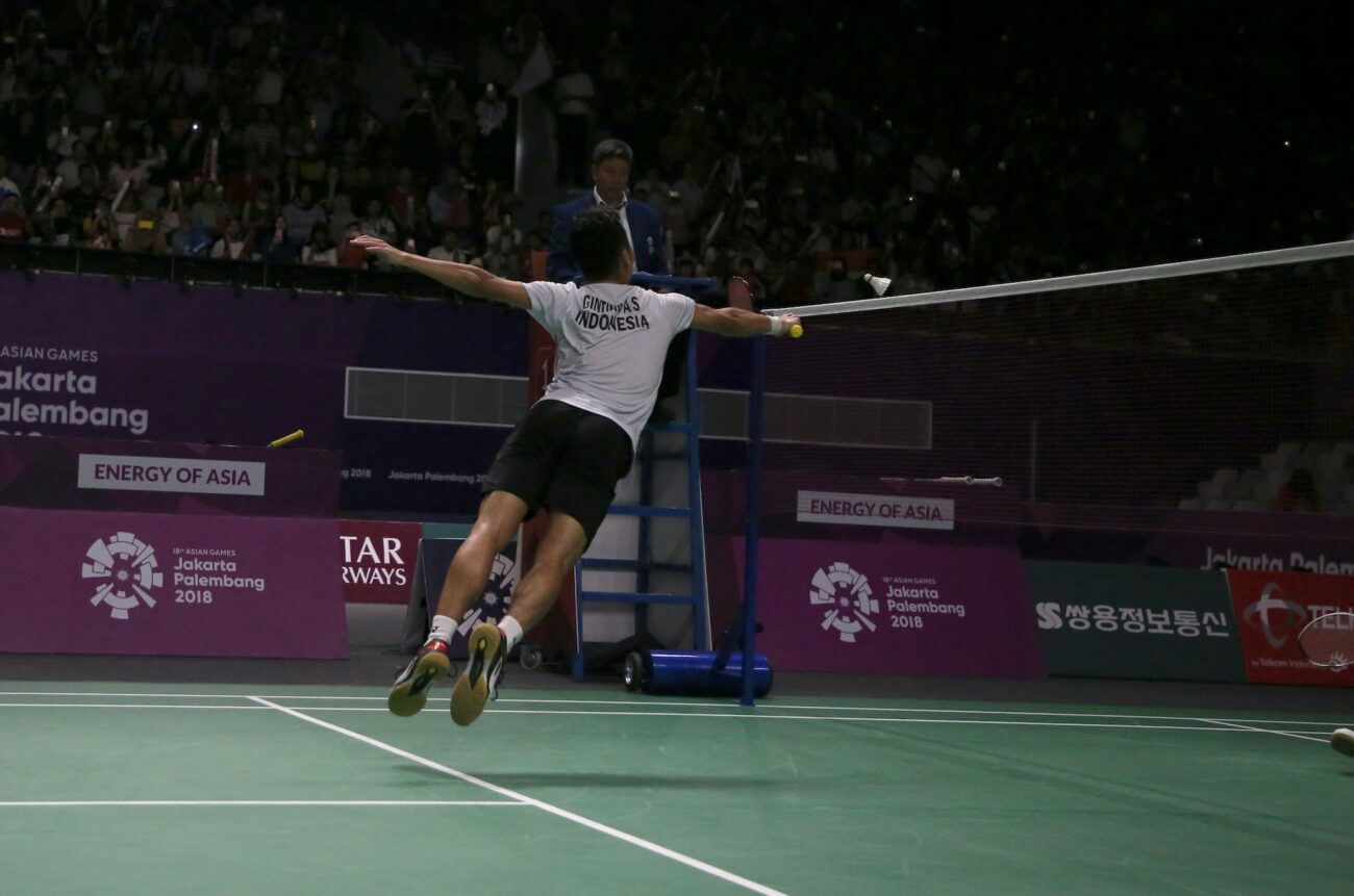 A Women Badminton Player flying in air for hit the shuttlecock