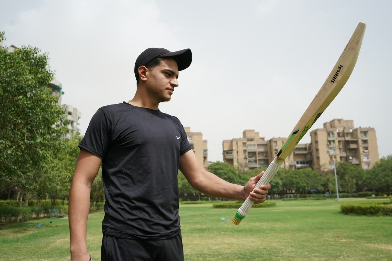 A Boy standing On ground with holding a Cricket bat in Left Hand
